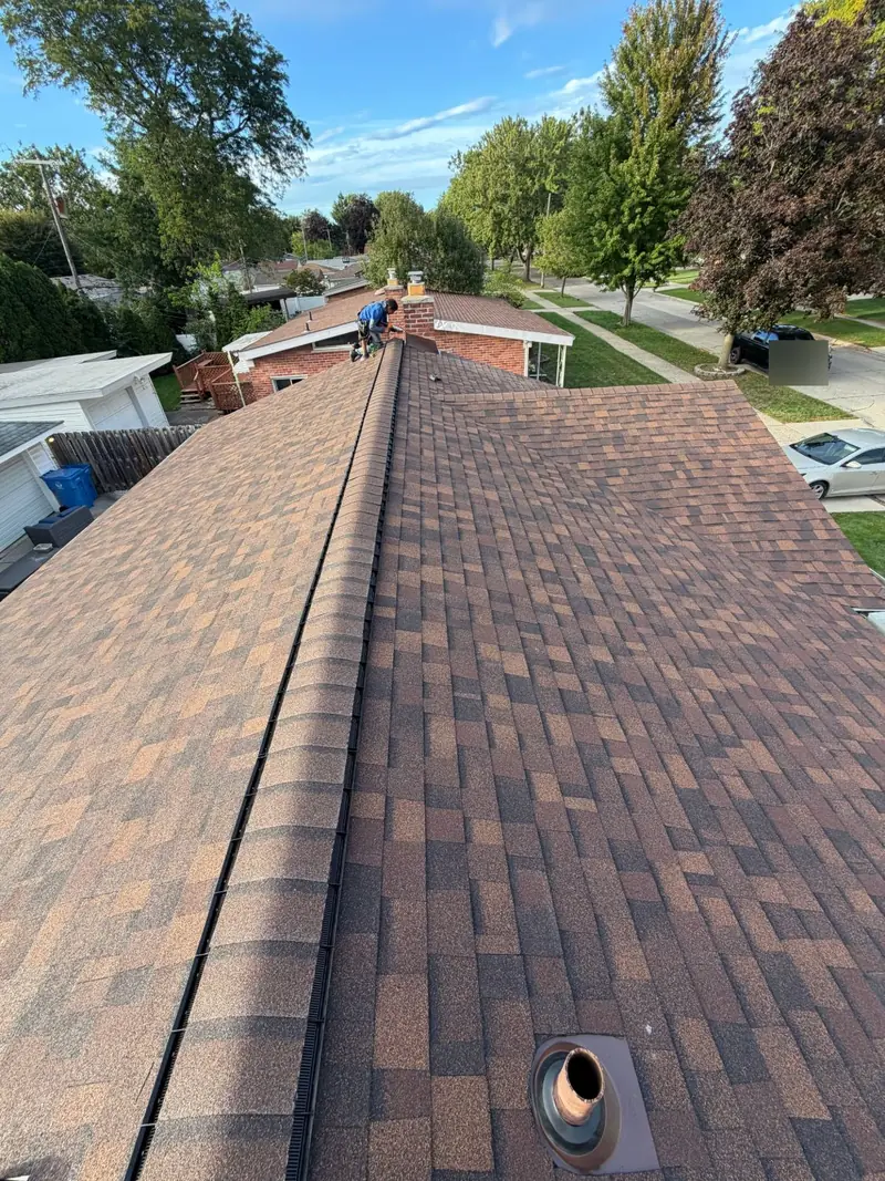 Finished brown-tone architectural shingle roof on a single-story home, with a ridge vent running under the ridge cap