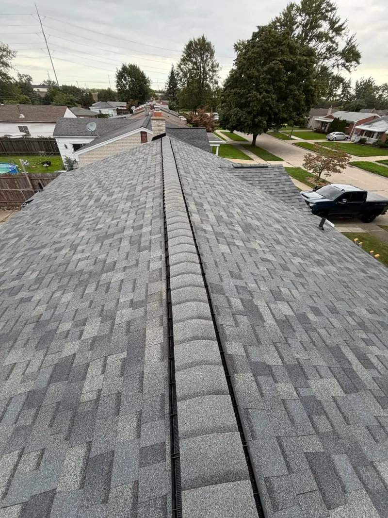 Finished grey architectural shingle roof on a single-story home, with a ridge vent running under the ridge cap